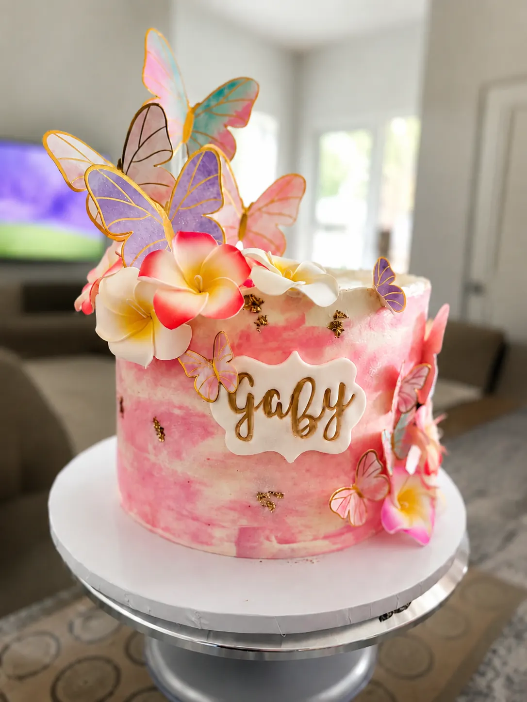 Torta rosa con mariposas pastel y flores decorativas.